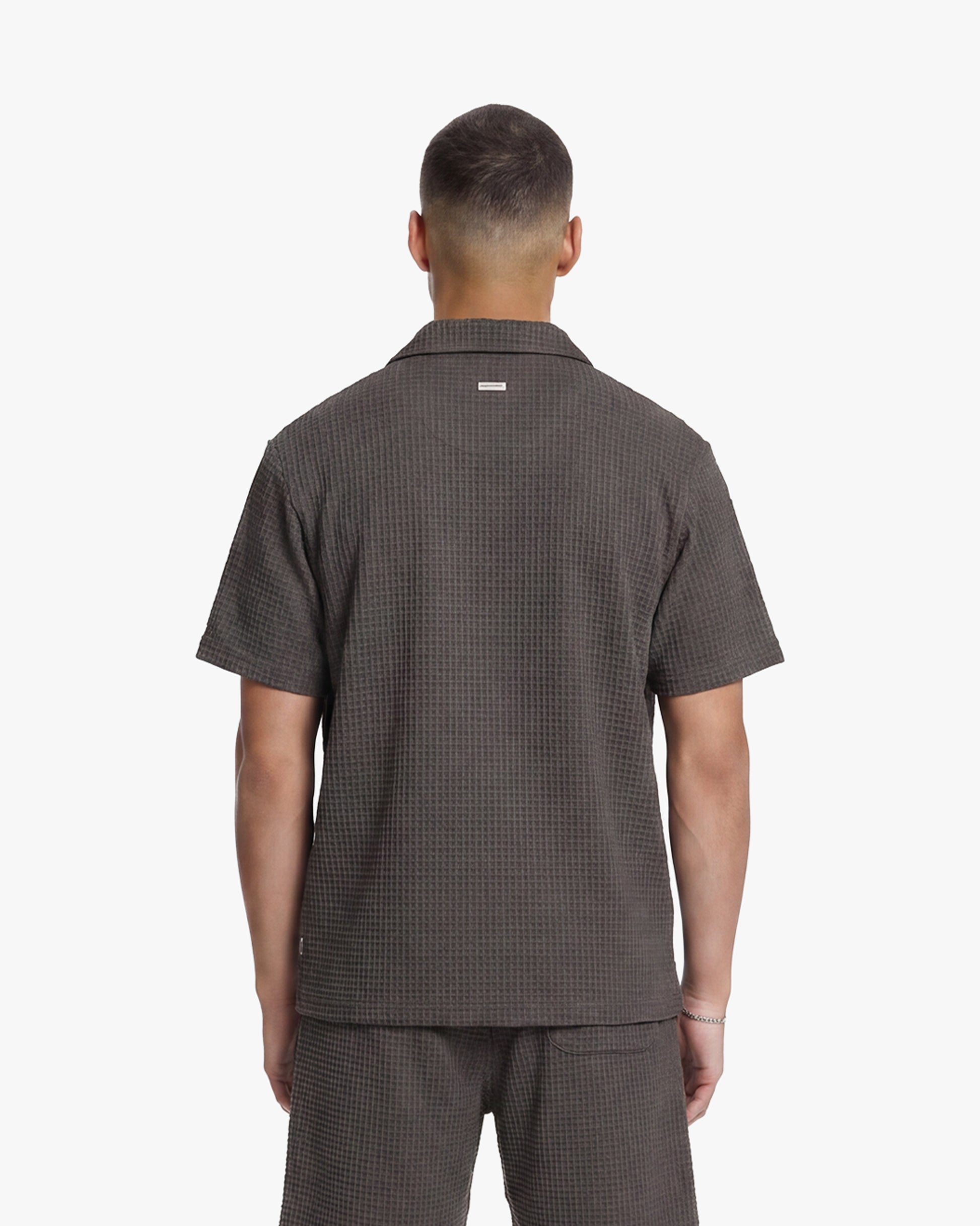 Men's washed brown waffle shirt with short sleeves and collar, seen from the back.